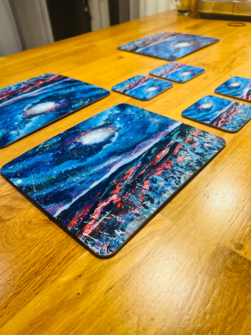 Set of four 23x19cm glossy wooden placemats featuring a vibrant blue night sky art print on a wooden dining table.