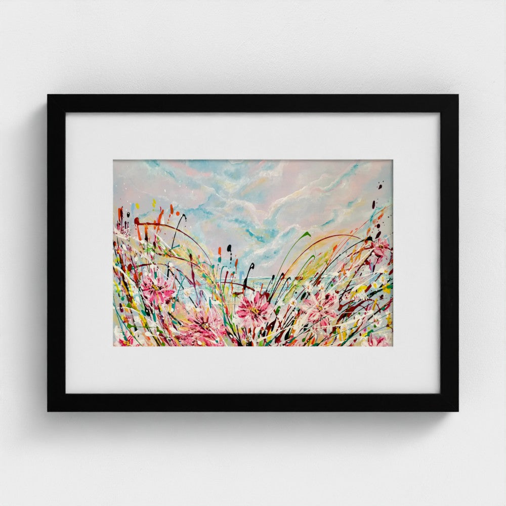 Black-framed abstract print with pink flowers, blue sky and colorful splatter