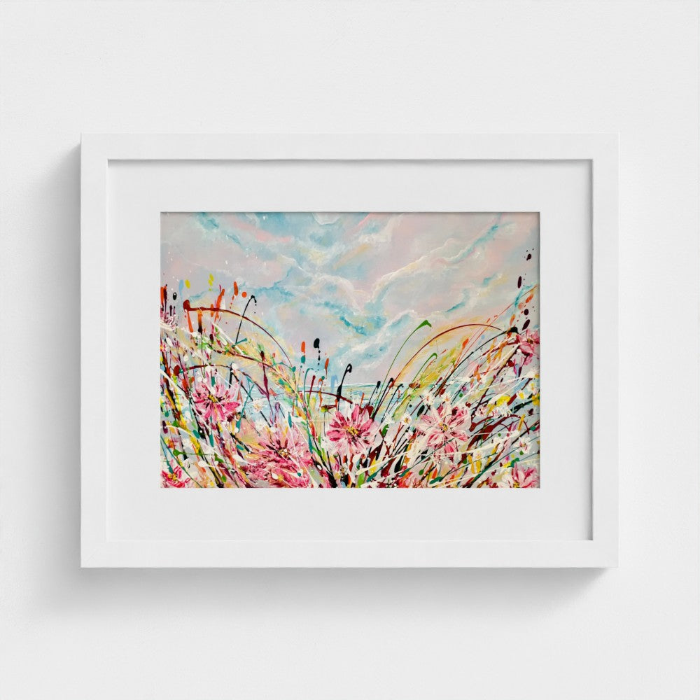 White-framed abstract print with pink flowers, blue sky and colorful splatter
