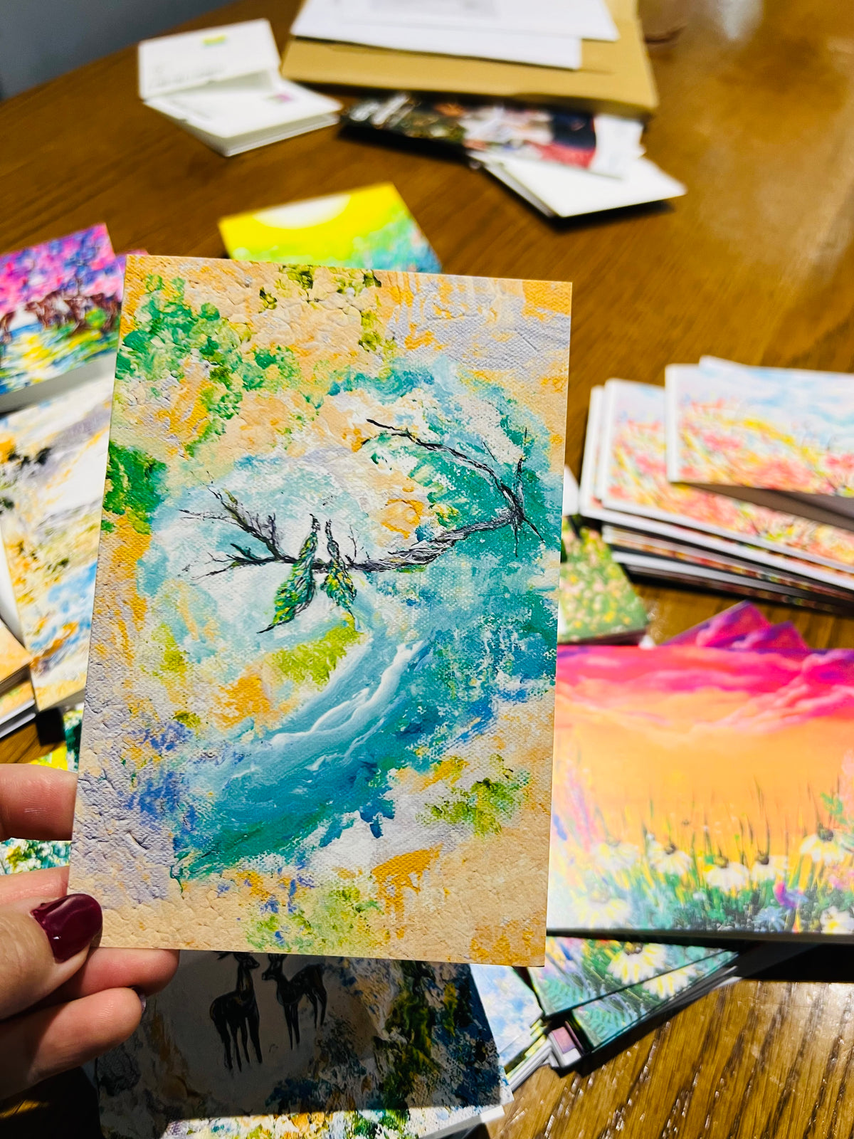 A6 folded greeting card with textured paper featuring an abstract floral painting in vibrant green, blue, and yellow tones.