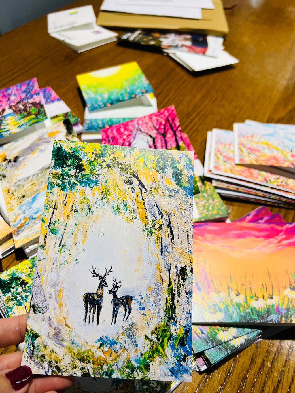 A6 portrait Christmas greeting card featuring a painted deer pair in a vibrant, textured forest scene on premium cardstock.