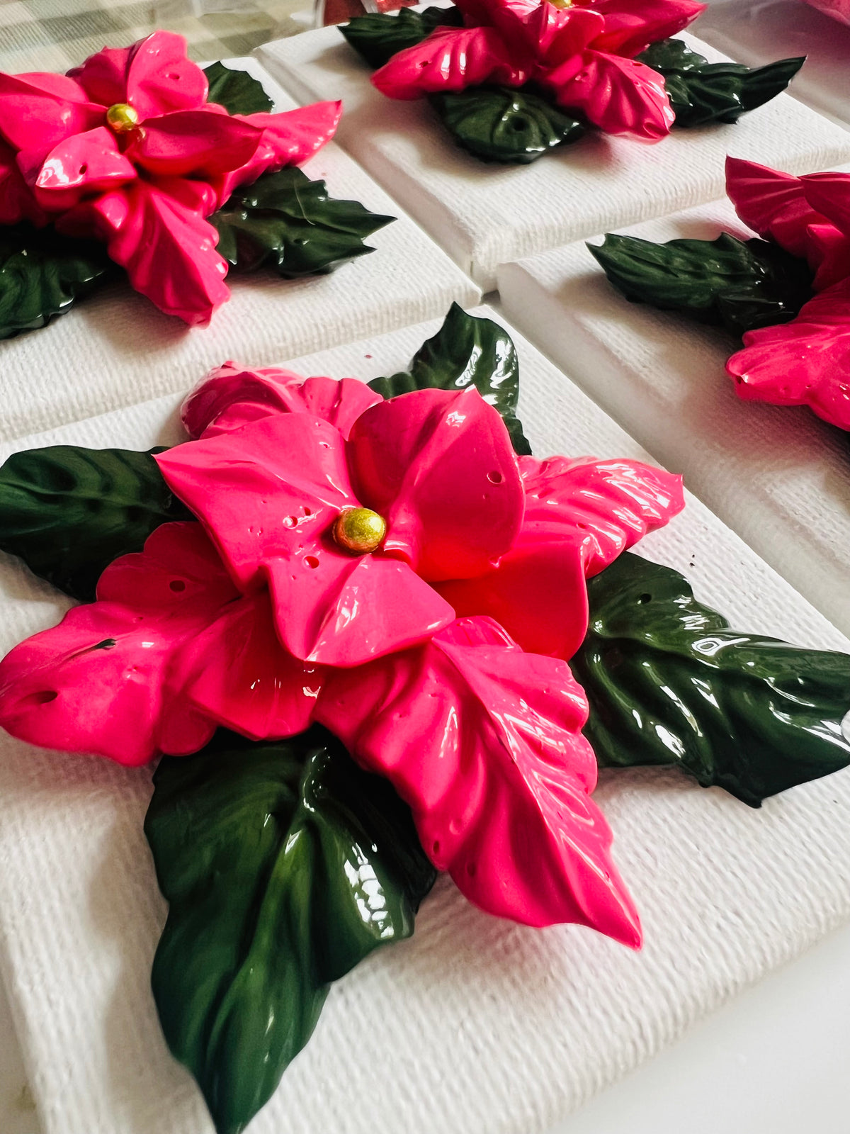 Textured pink poinsettia art on 7x7cm white cotton canvas with glossy green leaves and a gold center.