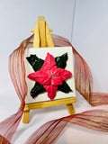 Textured red poinsettia art on a 7x7cm mini canvas displayed on a wooden easel with decorative sheer ribbon.
