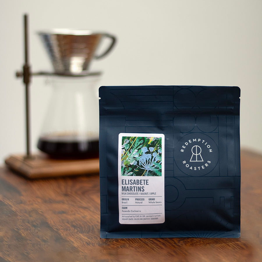 Dark blue coffee bag standing on table, ELISABETE MARTINS label and logo