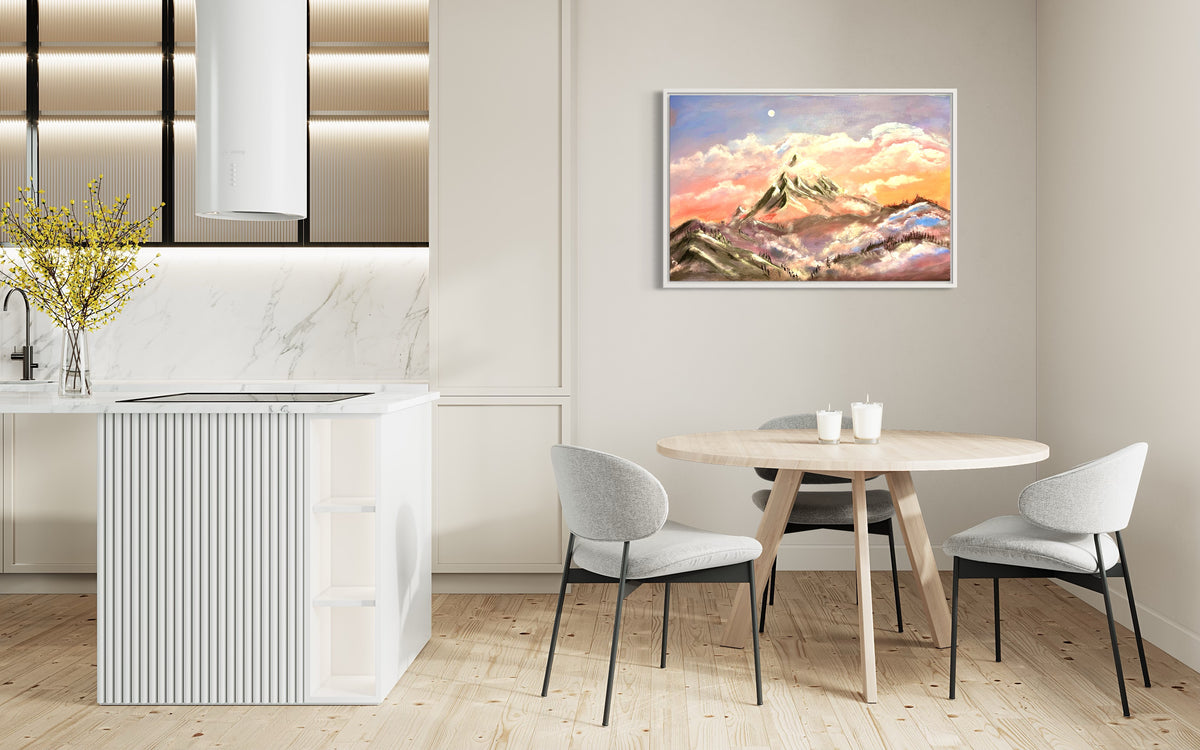 Framed mountain sunrise wall art above a round table, with snowy peaks and warm sky