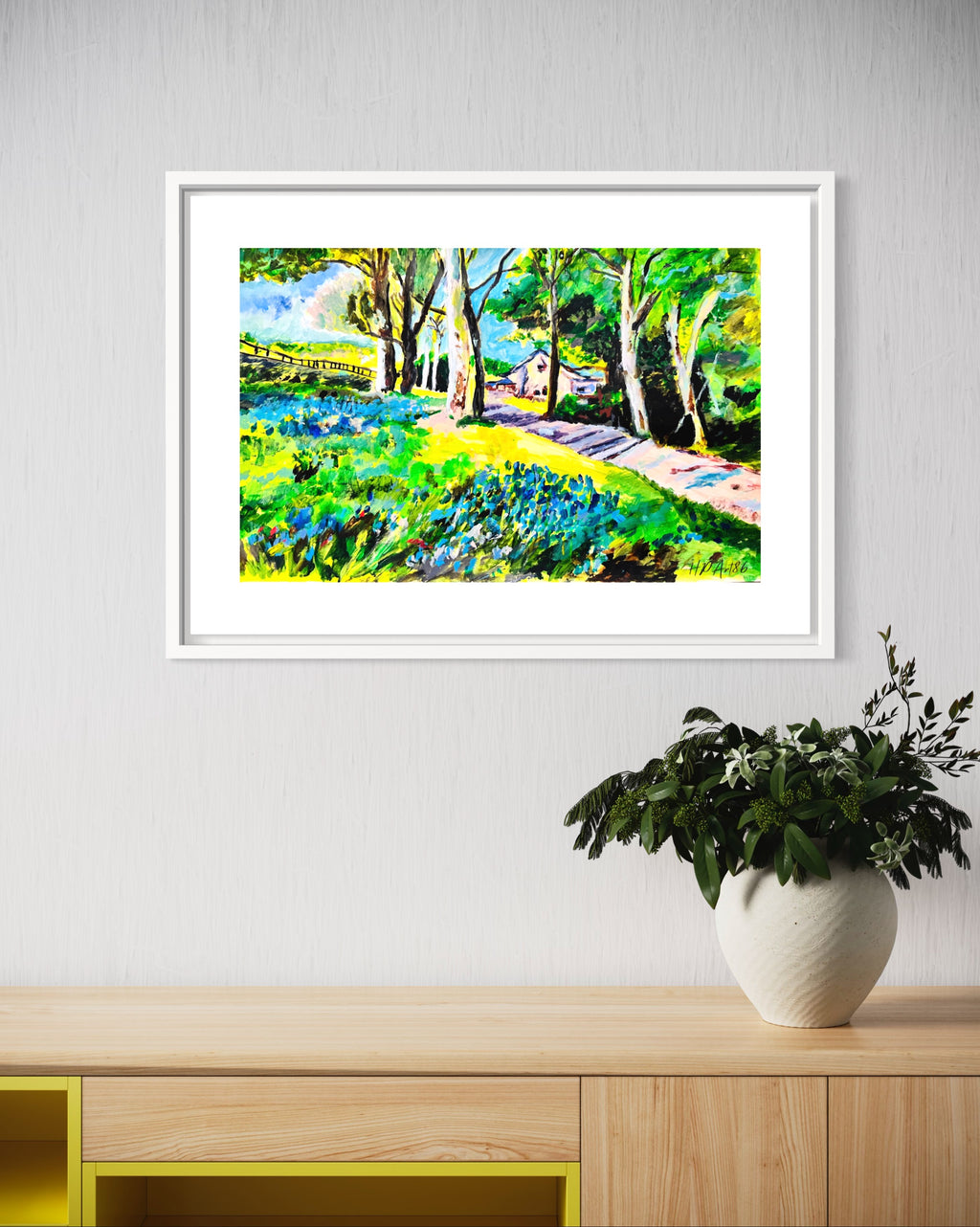 Framed watercolor landscape painting of bluebell meadow, trees, and path, white frame