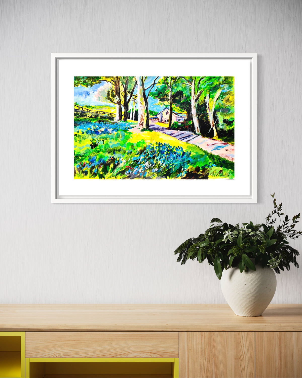 Framed watercolor landscape painting of bluebell meadow, trees, and path, white frame