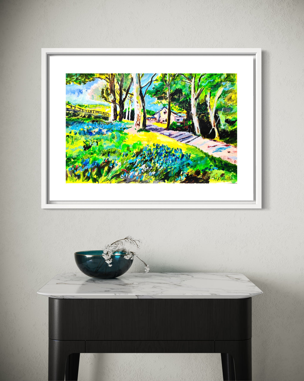 Framed watercolor landscape painting with bluebell field, trees, and path above a cabinet