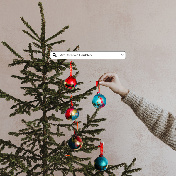 Hand-painted ceramic Christmas bauble hanging on a tree, blue and orange with gold