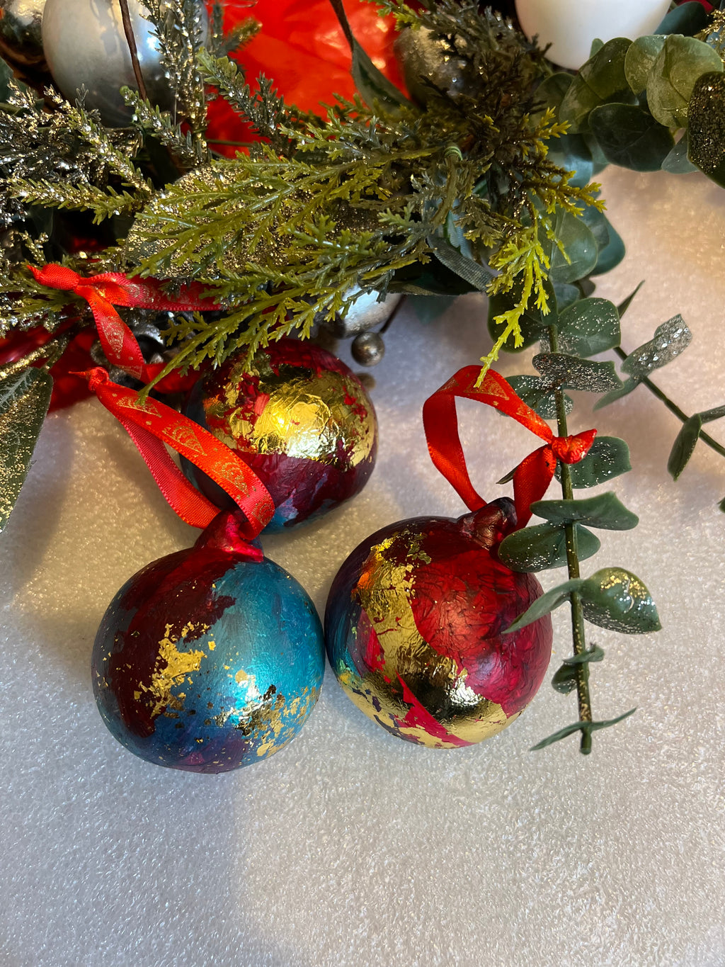 Hand-painted ceramic Christmas baubles with red ribbon bows, blue and gold leaf