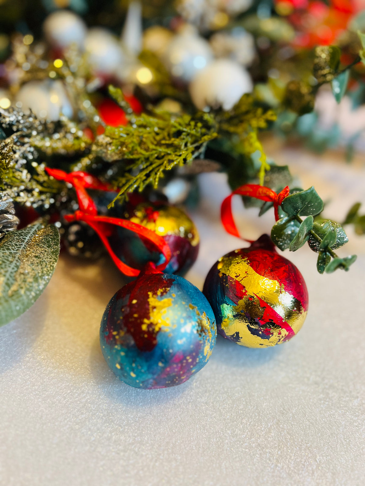 Hand-painted ceramic Christmas baubles with red ribbon bows, blue and gold leaf