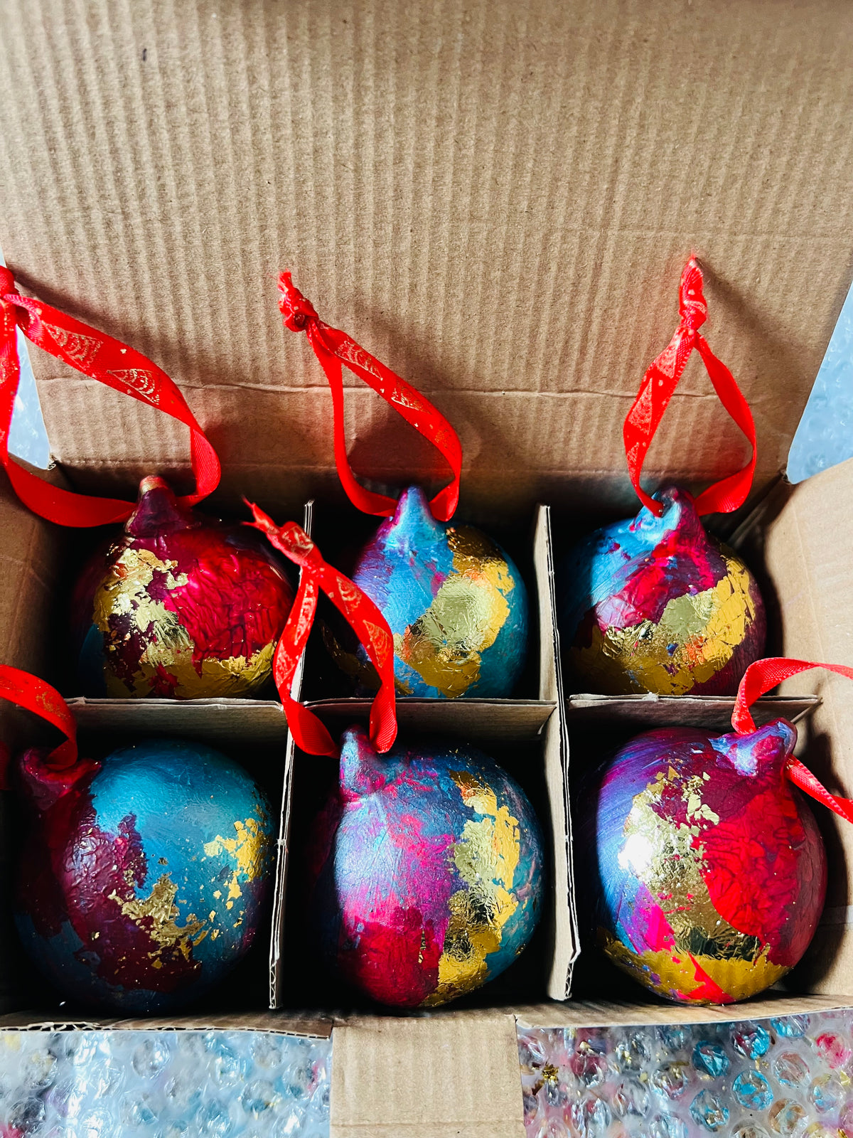 Assorted hand-painted ceramic Christmas baubles in a box, blue, red, orange with gold