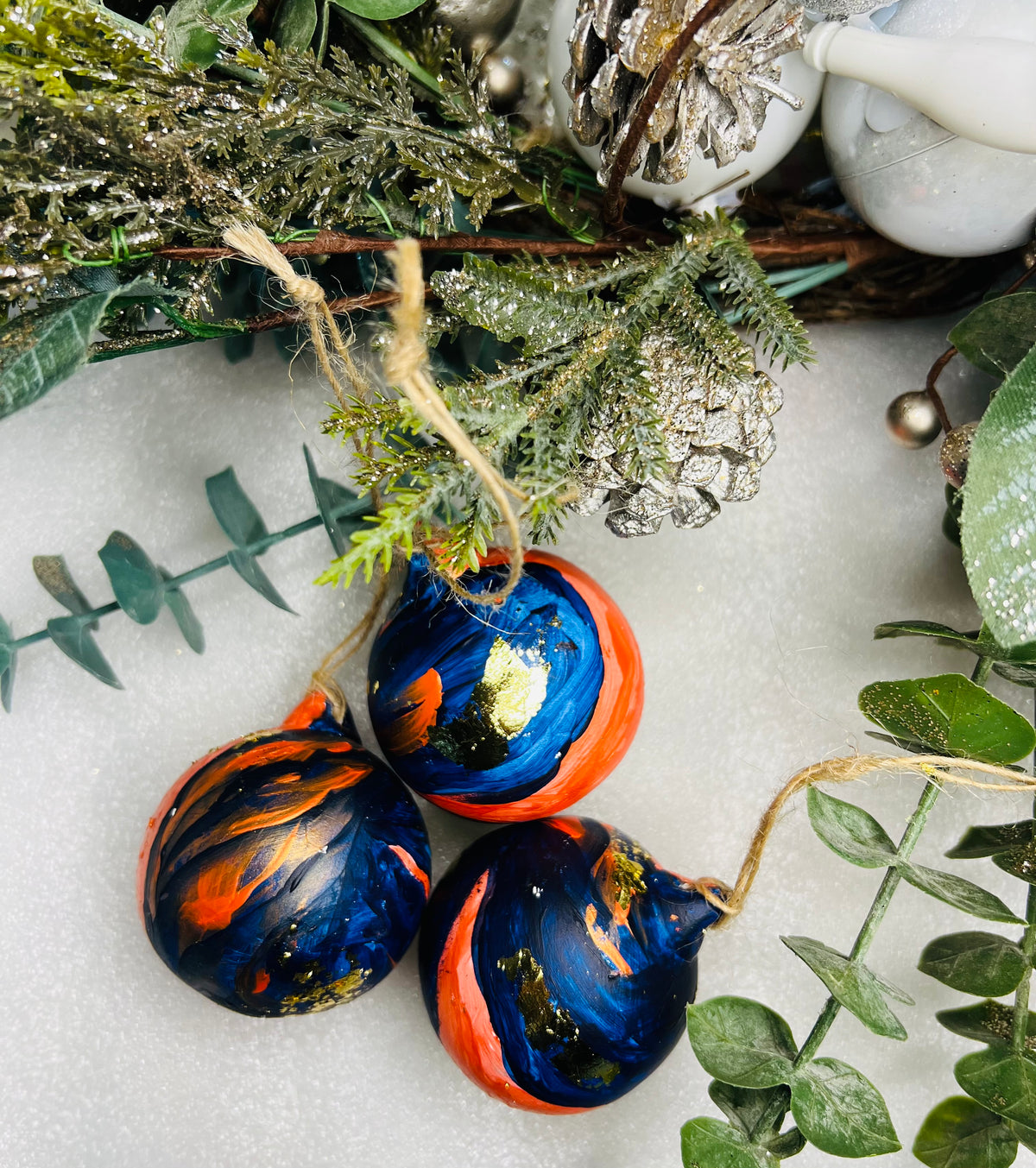 Hand-painted ceramic Christmas baubles with blue and orange swirls and gold leaf