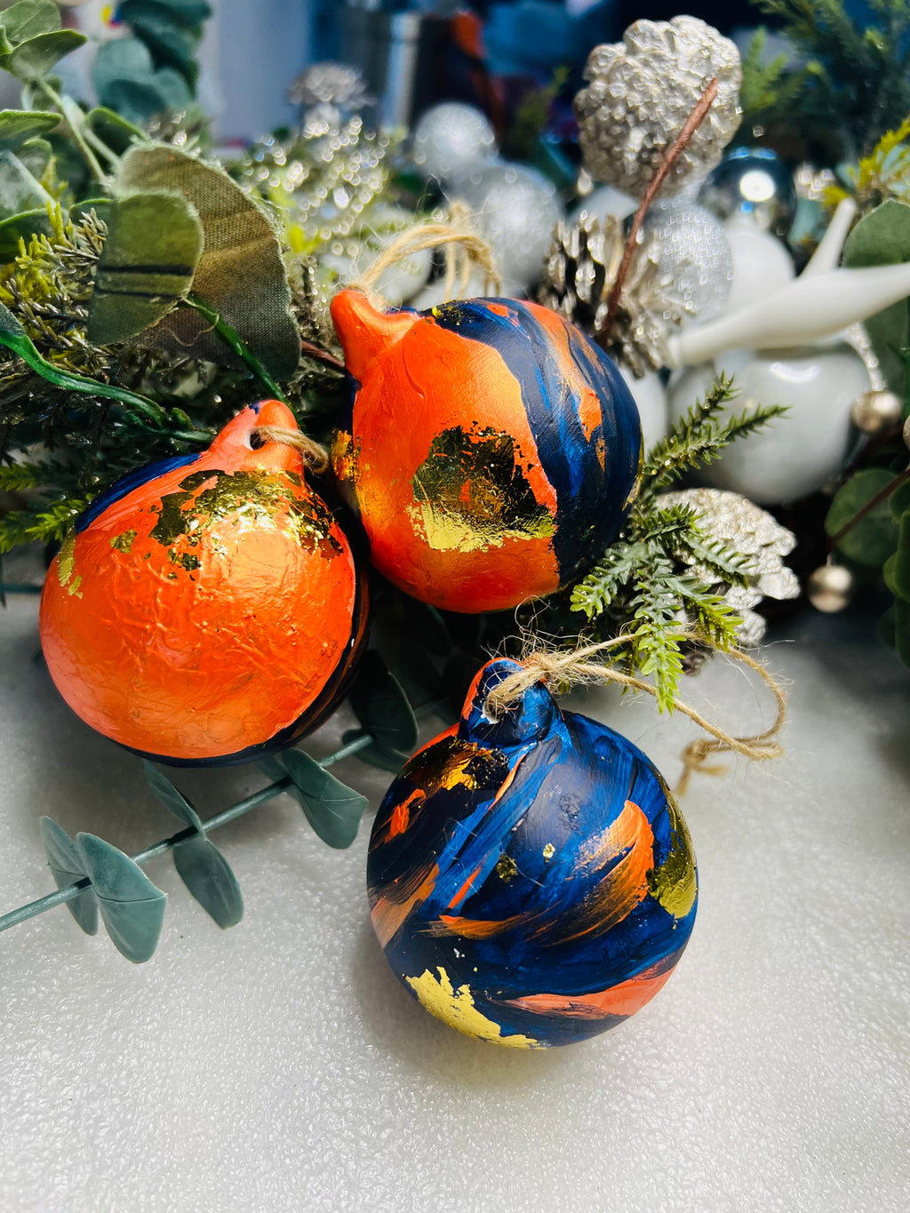 Hand-painted ceramic Christmas baubles, orange and blue swirls with gold leaf