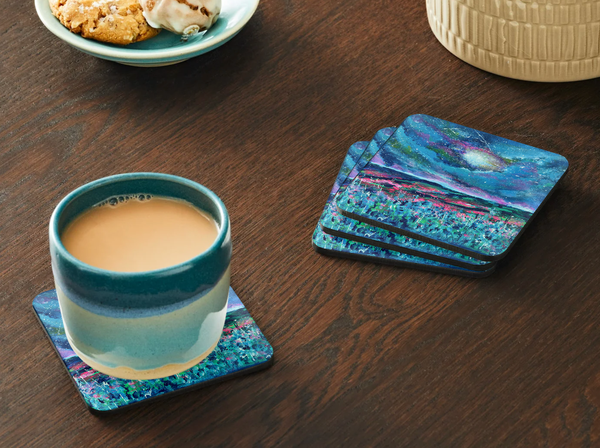 Glossy 9.5cm hardboard coaster featuring a dark blue wildflower sky design with a cork back on a wooden table.