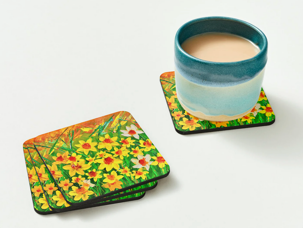 Glossy 9.5cm square hardboard coasters featuring vibrant yellow daffodil texture art, stacked with a ceramic mug.