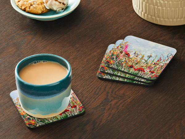 Glossy 9.5cm hardboard coasters featuring vibrant wildflower meadow artwork, set on a dark wooden table with a tea mug.