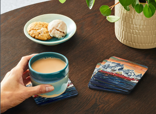 Square 9.5cm hardboard coaster featuring a vibrant fishing village art print with a glossy finish and cork backing.