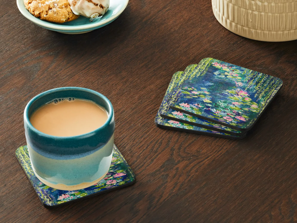 Glossy 9.5cm square hardboard coasters featuring a vibrant Waterlily Pond acrylic painting design on a wooden table.