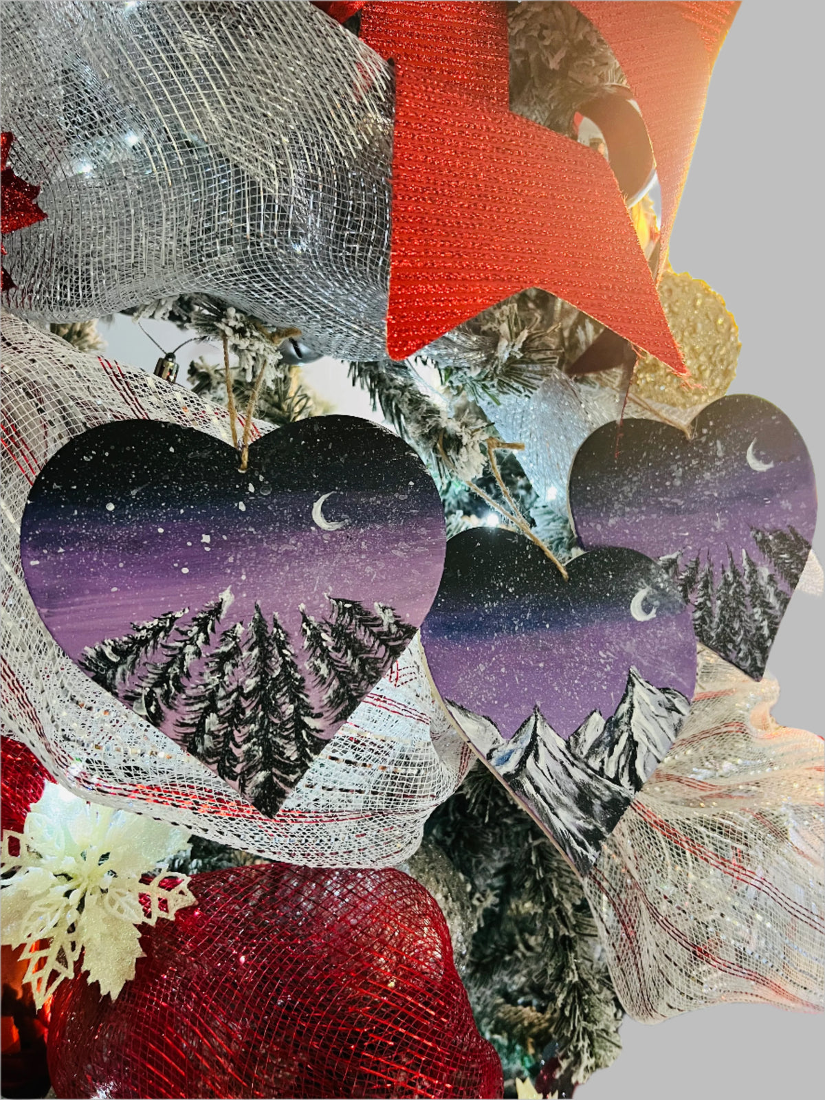 Hanging heart art decoration, two hearts showing starry purple night sky with pine trees and mountains