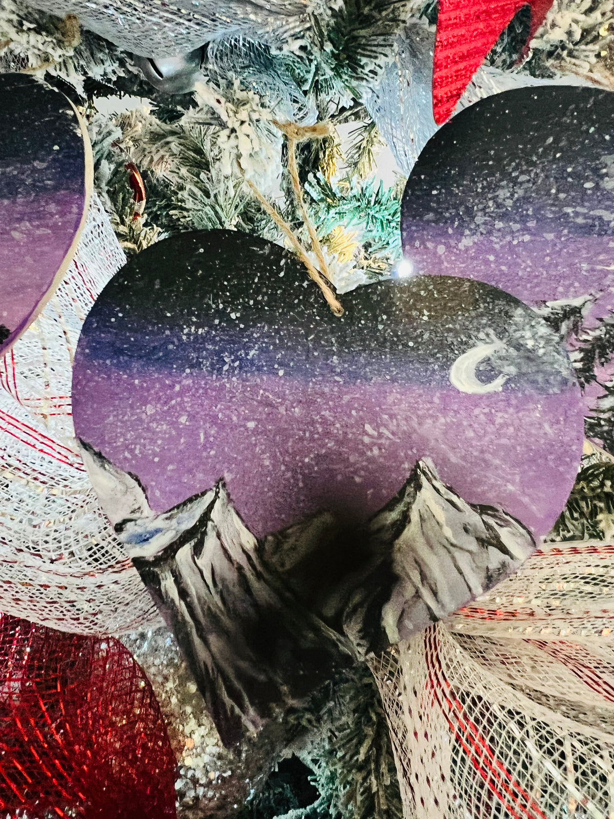 Hanging heart art decoration, dark sky with crescent moon, purple glow, pine forest and snowy peaks