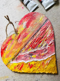 Hanging heart wall decoration with textured abstract red, yellow and pink paint, jute loop.