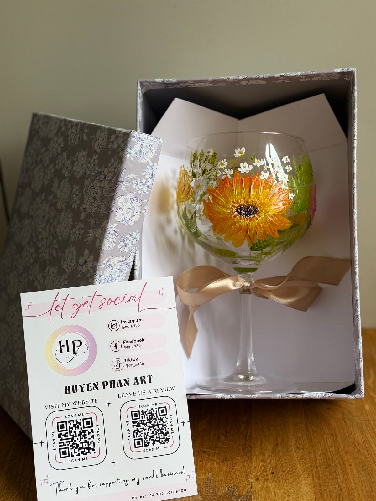 Gift box set with hand-painted stemmed wine glass showing bright orange flower