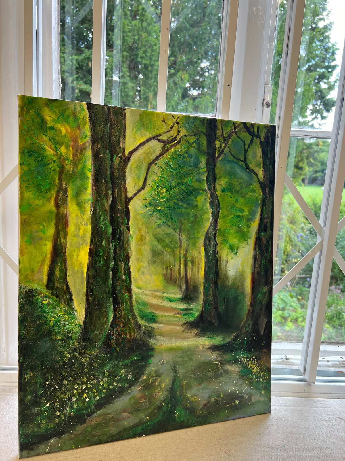 Framed landscape painting on canvas with green trees and a sunlit path