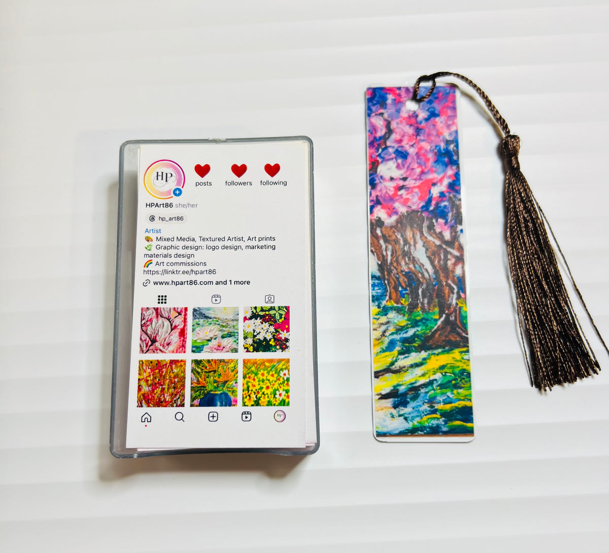 Metal bookmark with blue mountain and lake artwork and black tassel.