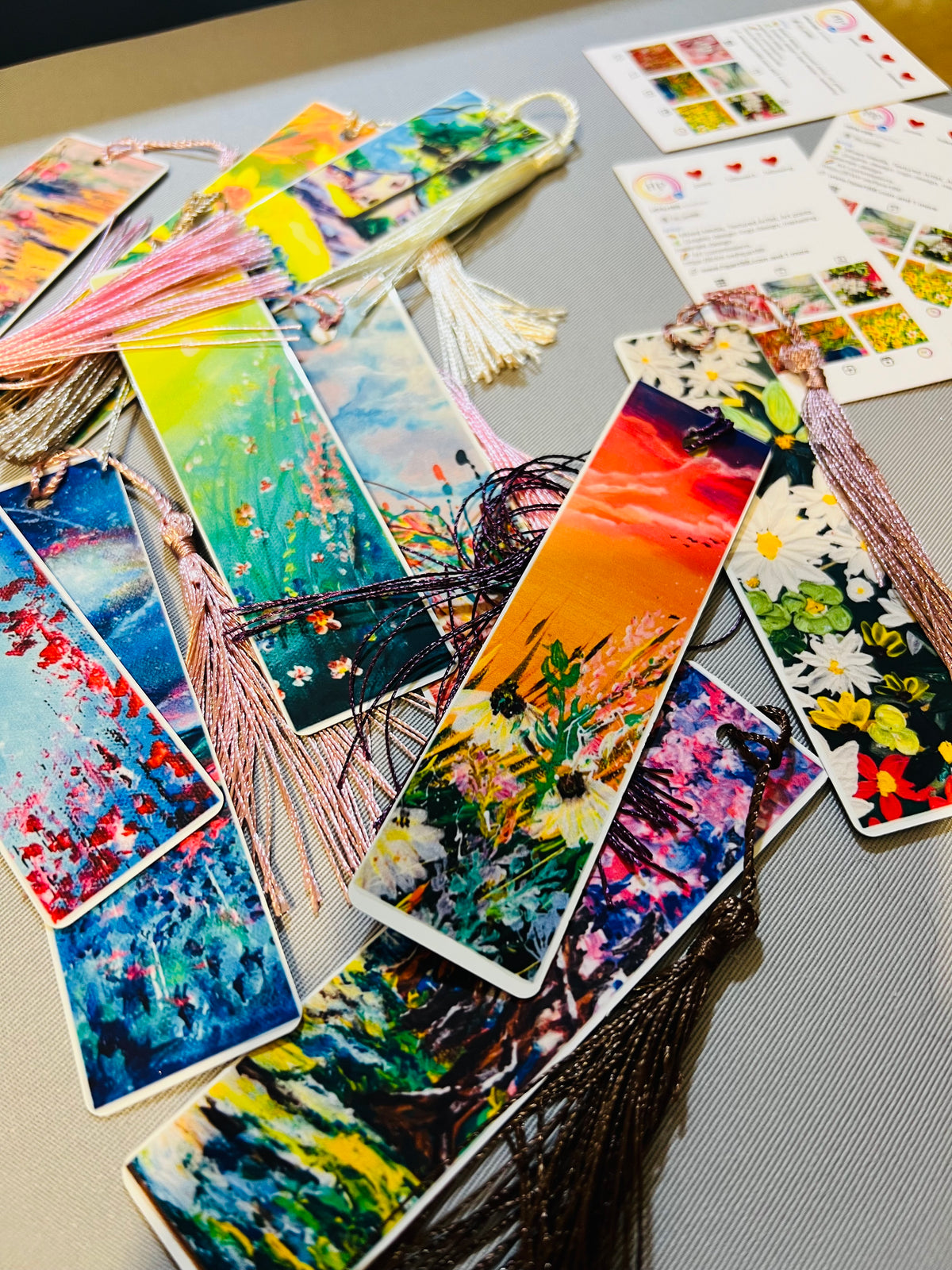 Metal bookmarks with colorful abstract art prints and pink tassel fringes.