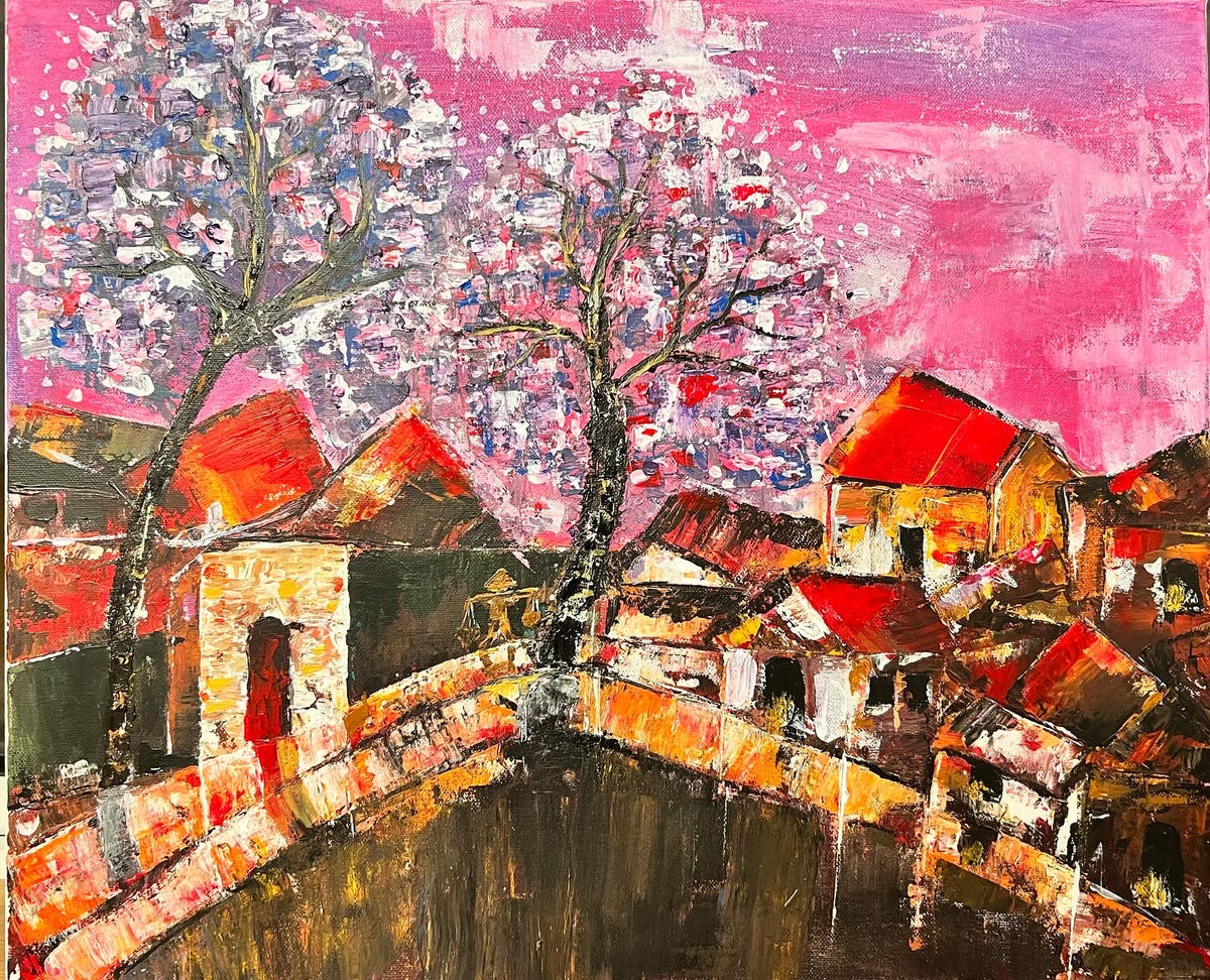 Framed cityscape wall art with colorful buildings, curved bridge, and a flowering tree under pink sky.