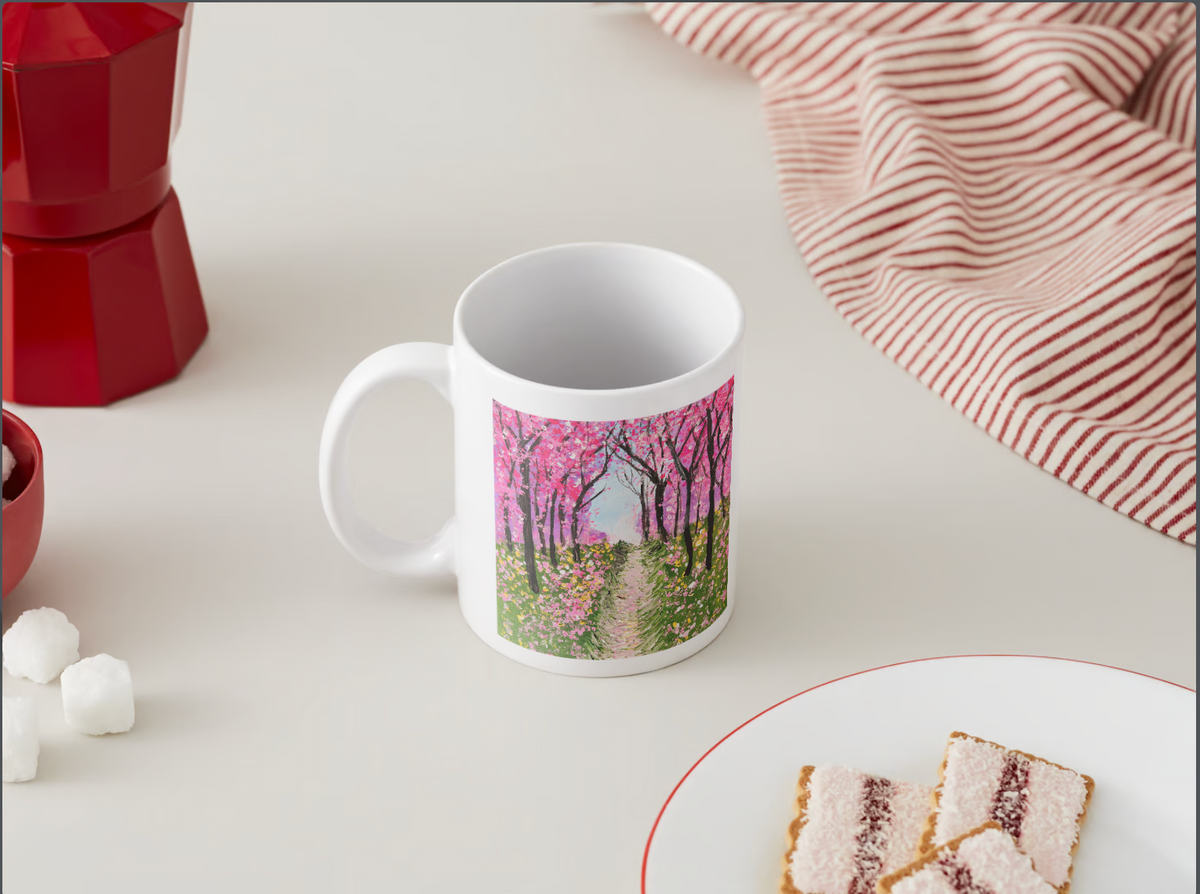 White ceramic mug on a tabletop with cherry blossom tree path graphic