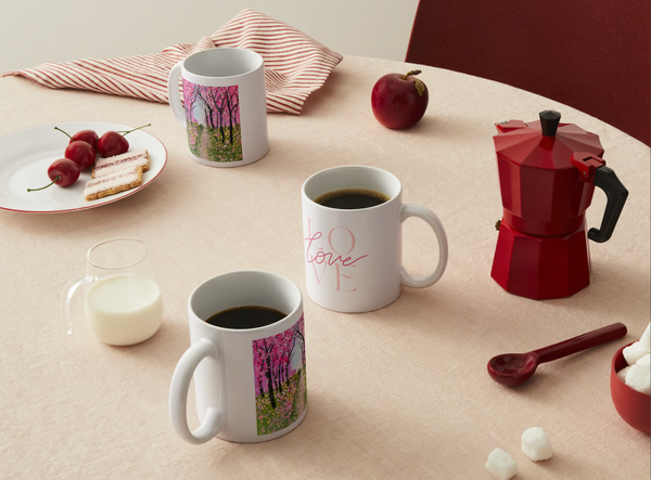 Cherry blossom and “Love” printed ceramic mugs on a table with red coffee pot