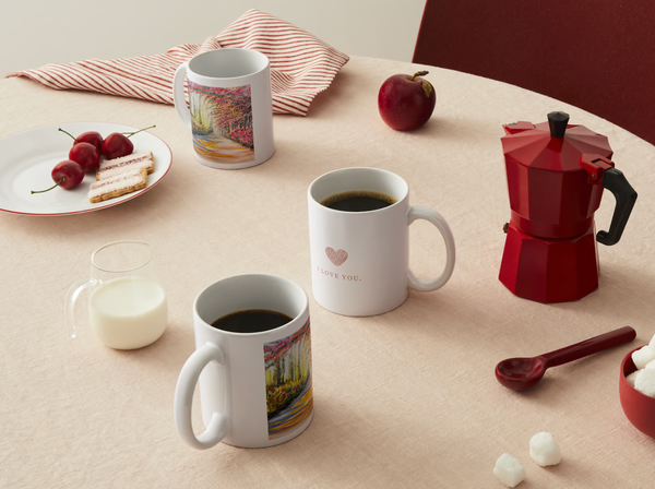 White ceramic mugs on display; front mug has colorful landscape print and 'I LOVE YOU'