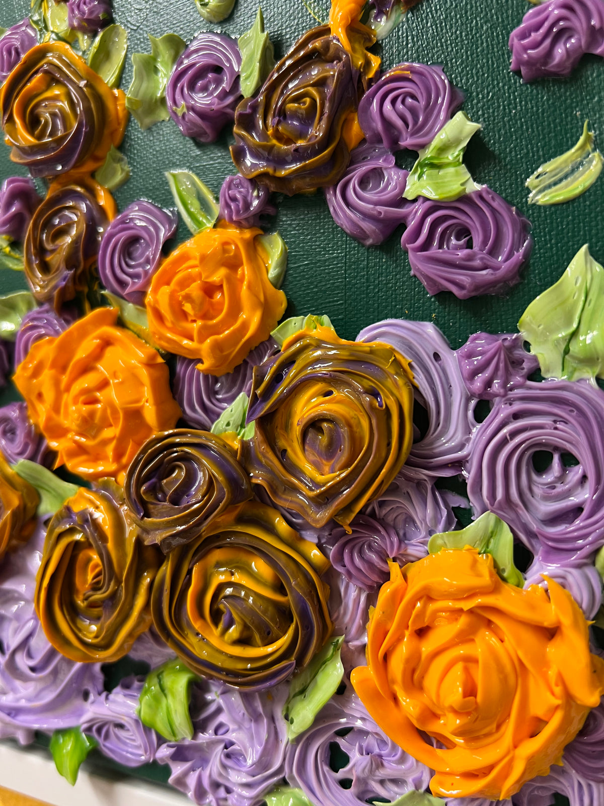 Close-up textured floral wall art with orange, gold, and purple rose rosettes and green leaves