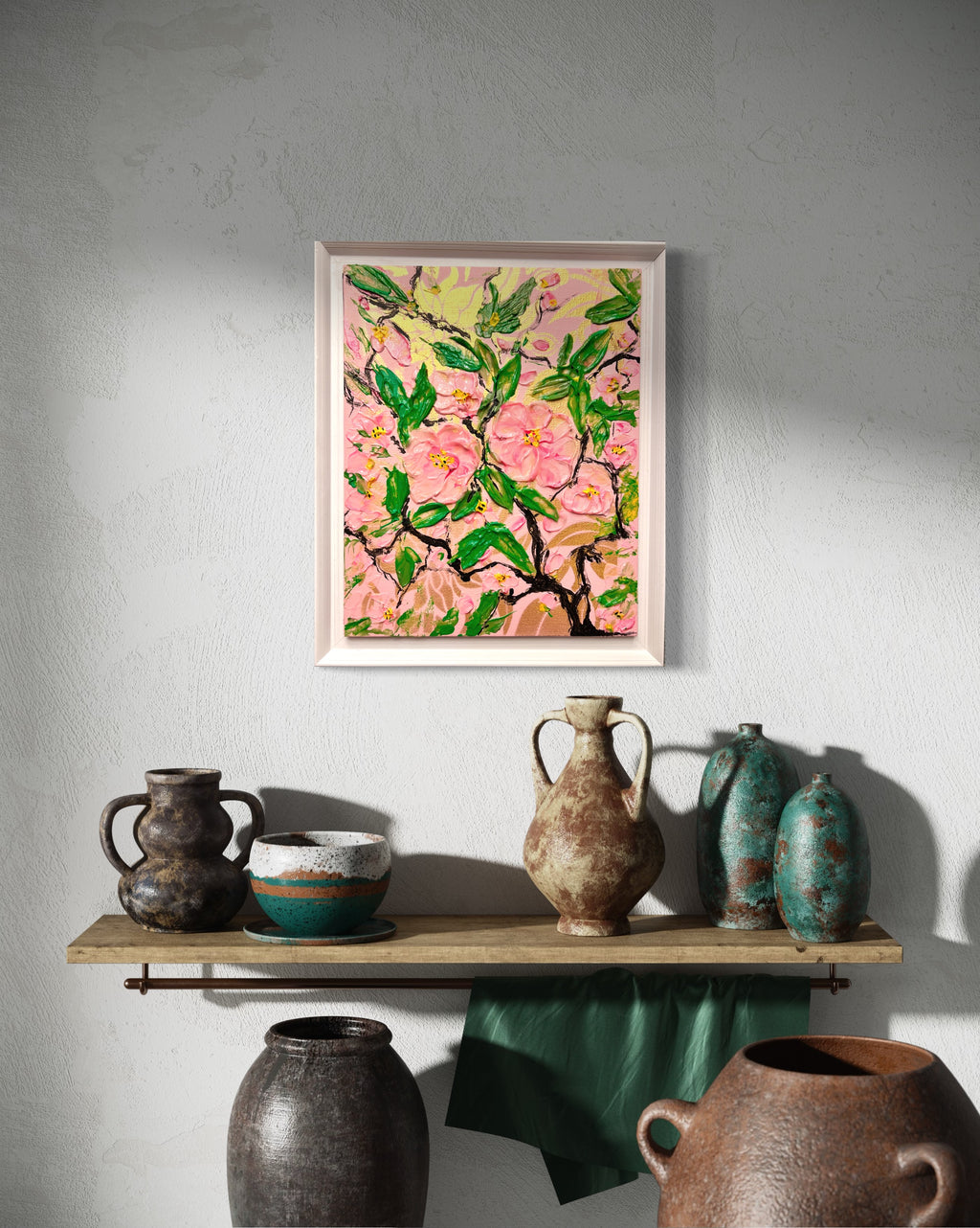Framed pink cherry blossom painting above a decorative shelf