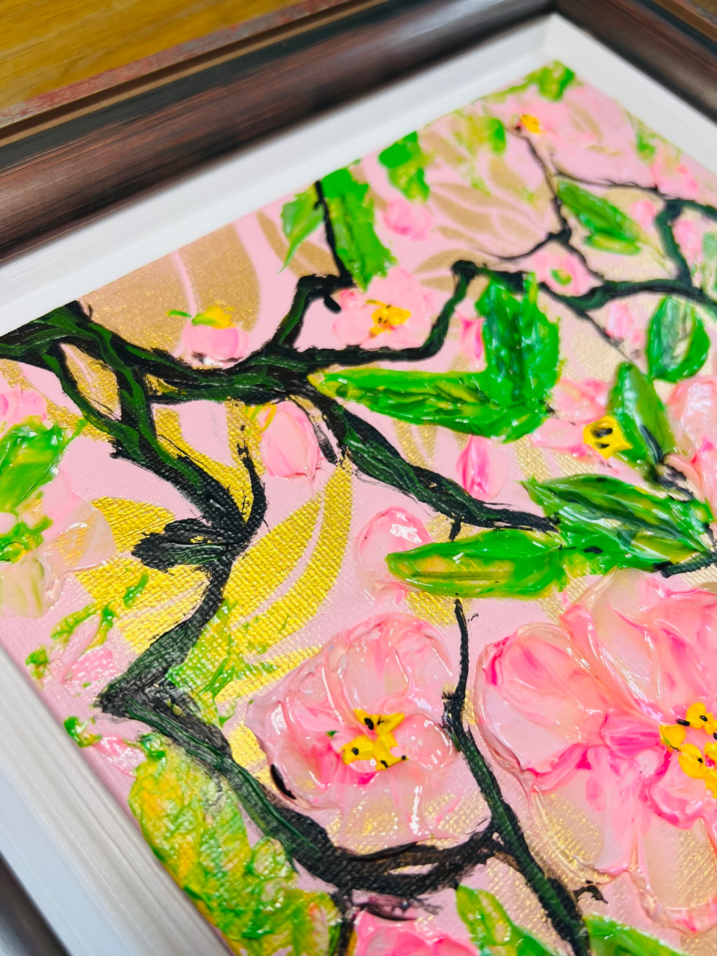 Angled close-up of framed cherry blossom painting with textured pink flowers