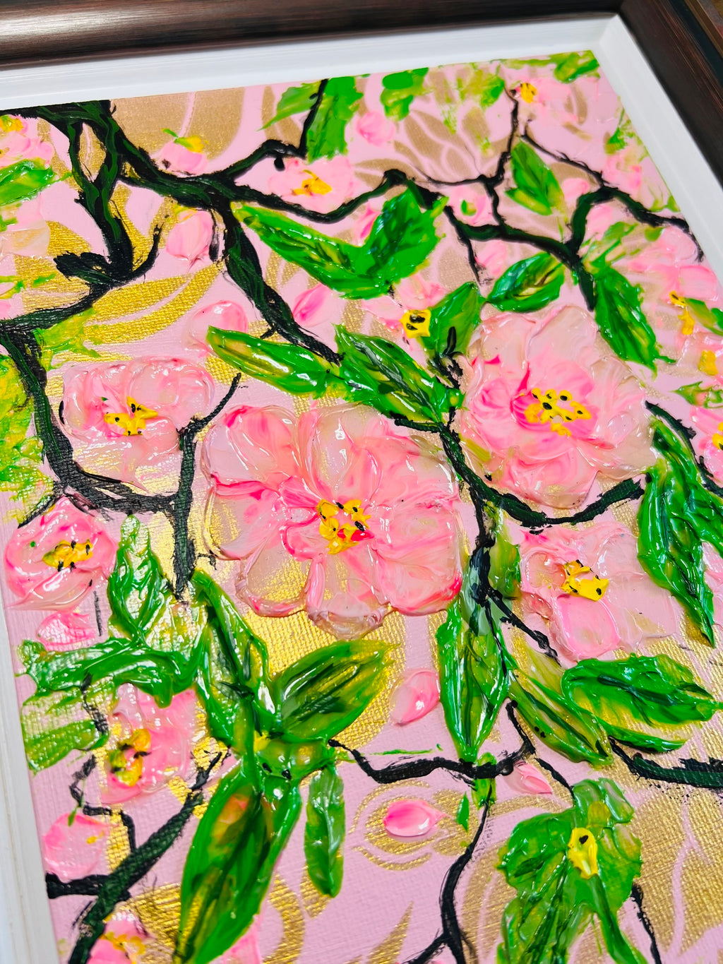 Tight close-up of framed cherry blossom painting with detailed pink blooms