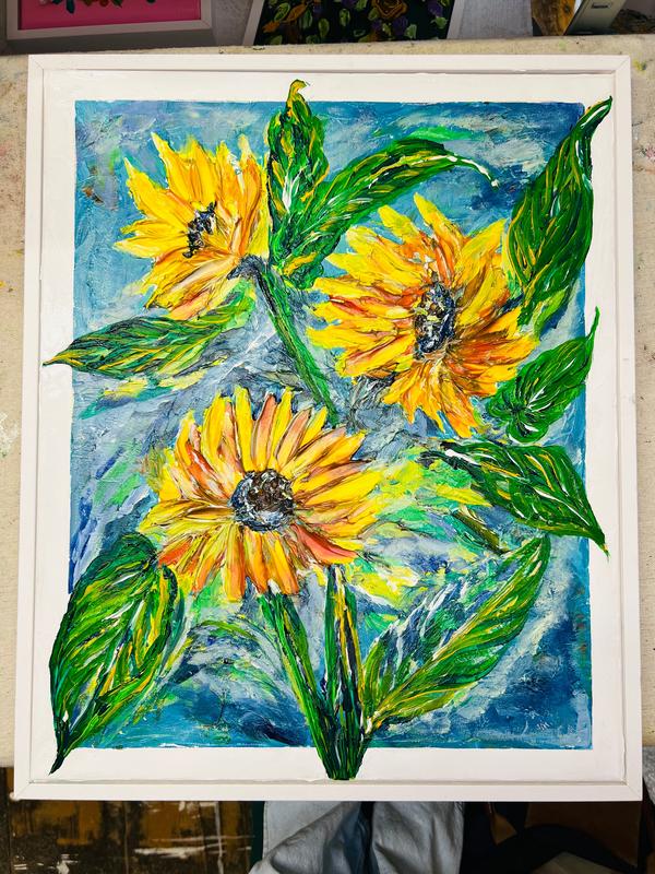 Framed sunflower landscape painting displayed in a white frame with three yellow flowers.