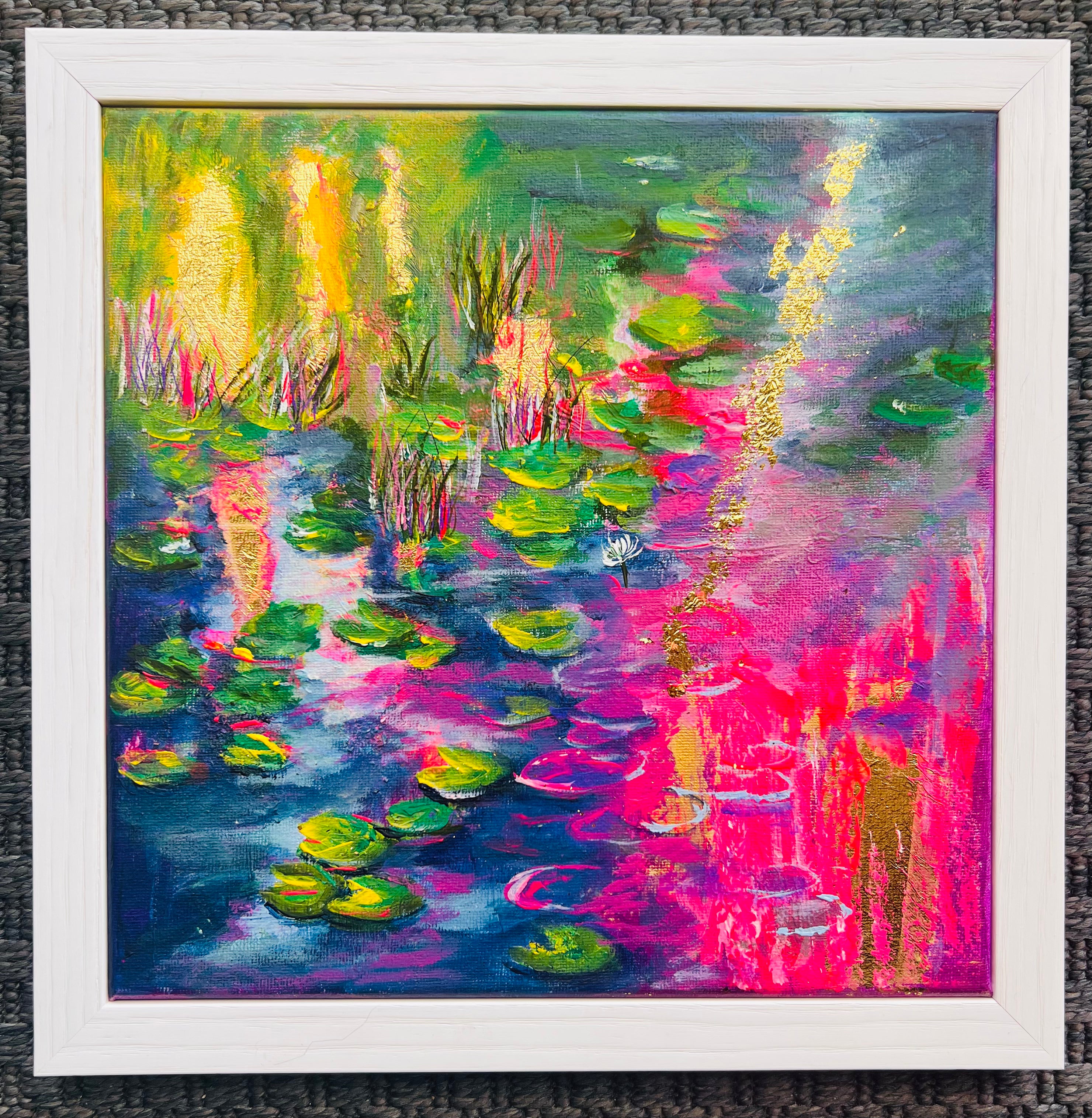 Close-up of framed abstract acrylic painting with neon pink water lilies and gold leaf detailing