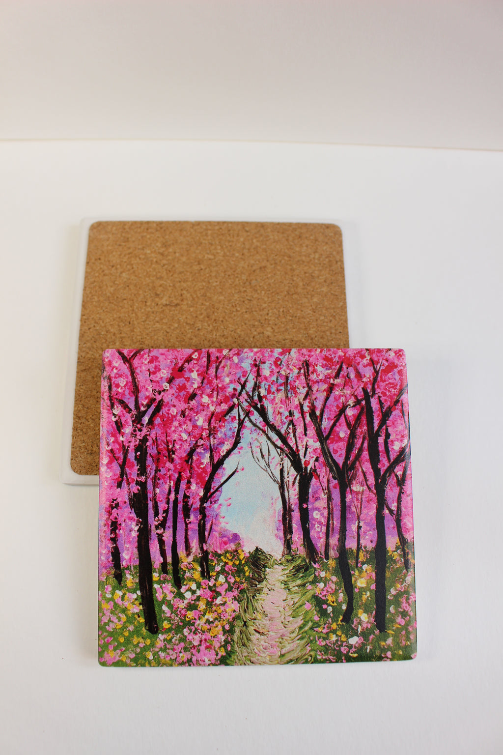 10x10cm square ceramic coaster featuring a hand-painted cherry blossom forest scene with a protective cork backing.