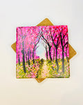 Square ceramic coaster with pink cherry blossom path artwork, gold decorative backing behind