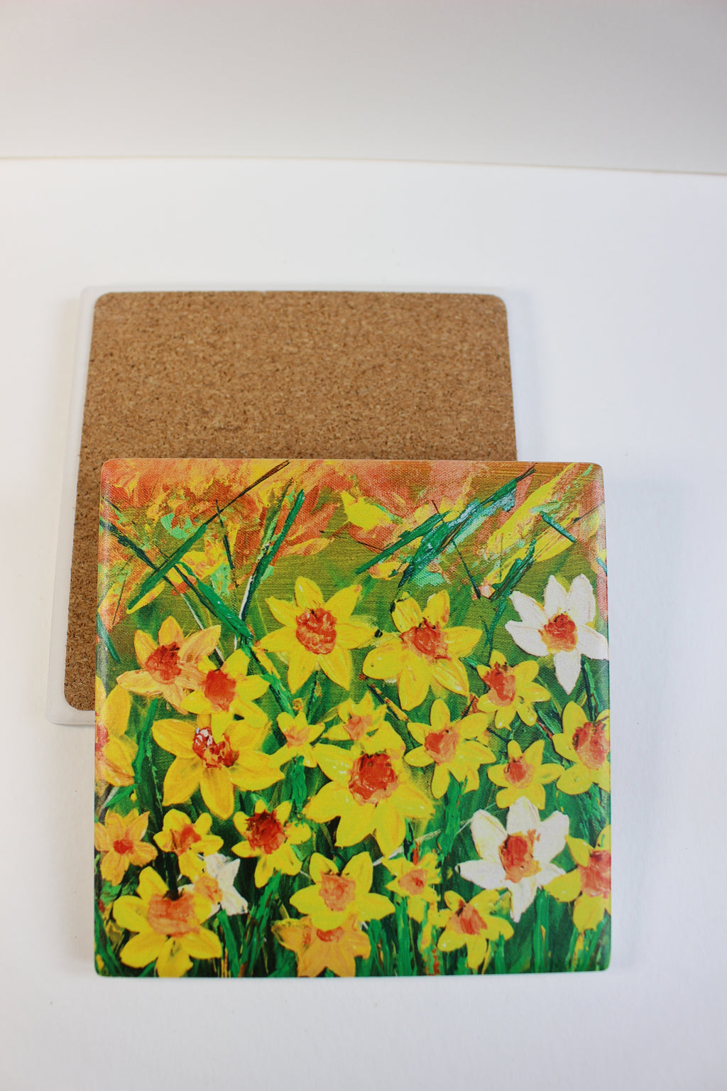 10x10cm square ceramic coaster featuring a vibrant hand-painted daffodil art print with a protective cork backing.