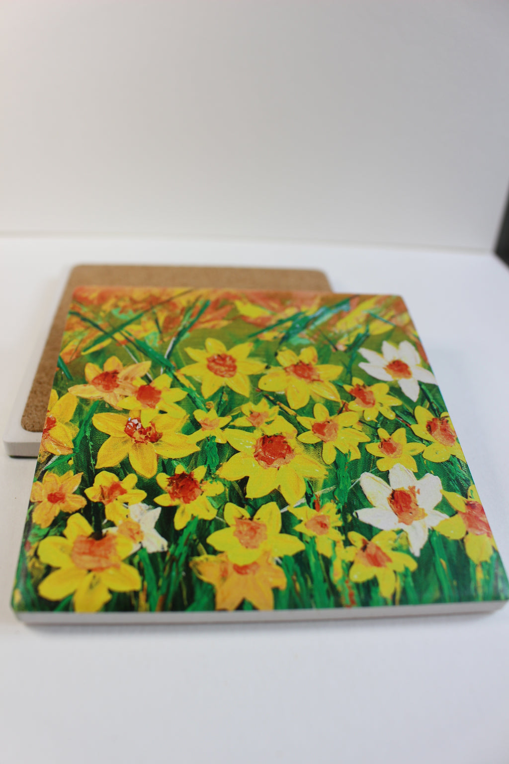 10x10cm square ceramic coaster featuring a vibrant hand-painted yellow daffodil floral print with a protective cork backing.