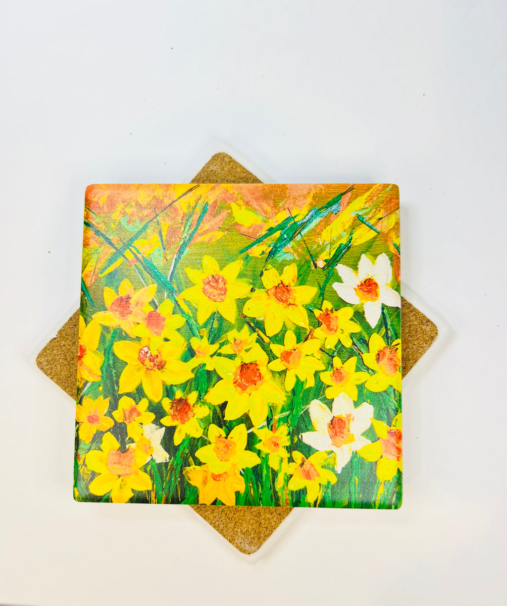 Square 10x10cm ceramic coaster featuring a vibrant hand-painted daffodil art print with a protective cork backing.