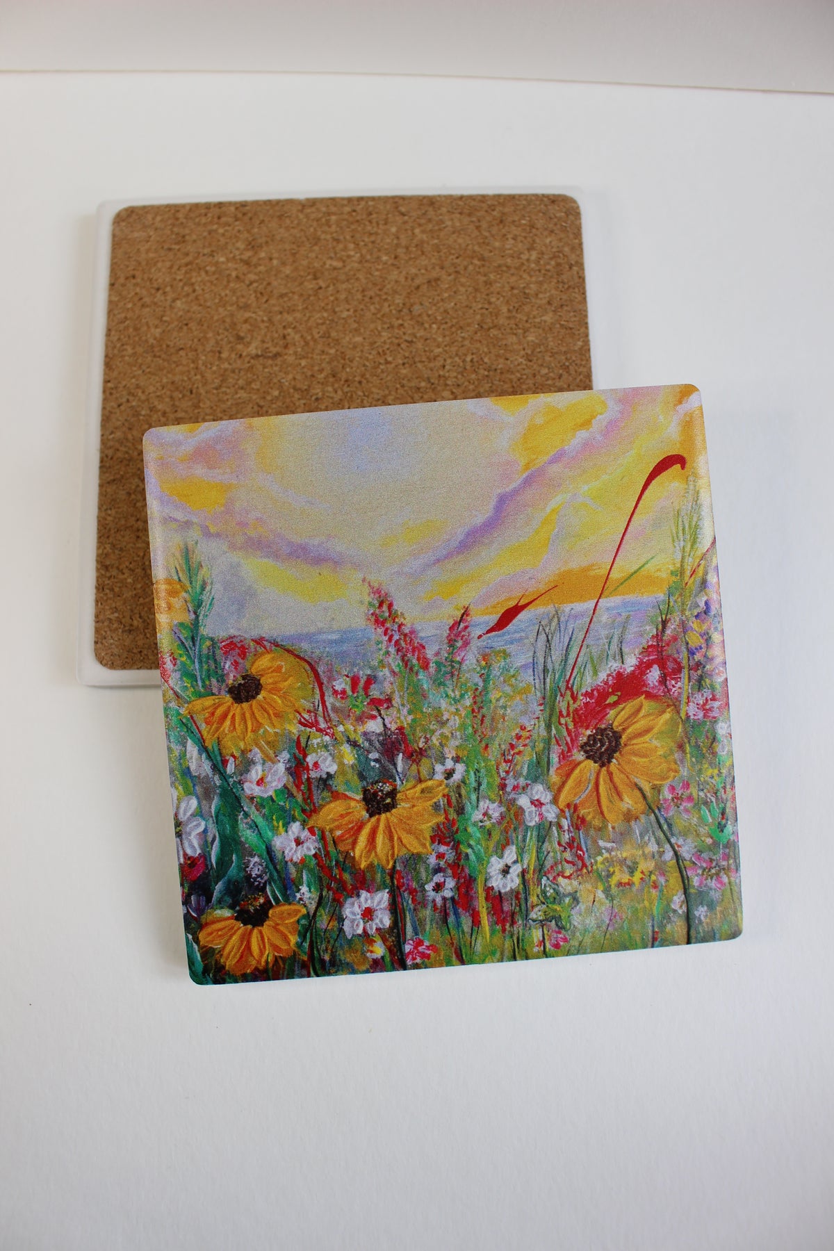 10x10cm square ceramic coaster with a colorful hand-painted daisy meadow art print and a protective cork backing.
