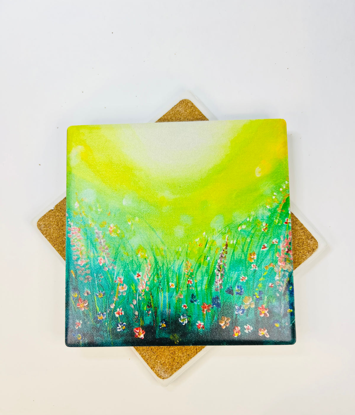 10x10cm square ceramic coaster featuring a vibrant green field art print with colorful wildflowers and a protective cork backing.