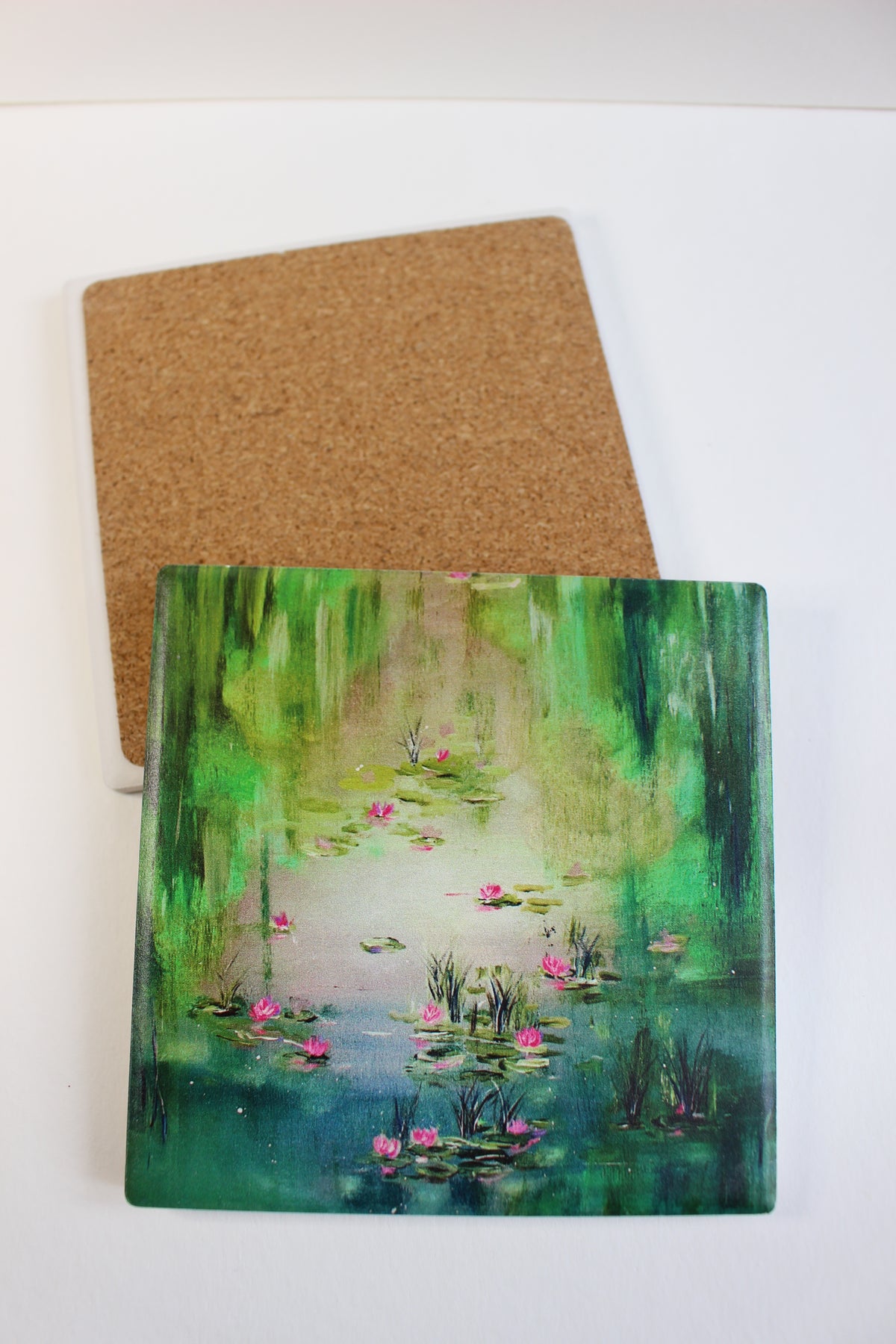 10x10cm square ceramic coaster with a hand-painted water lily pond design and protective cork backing.