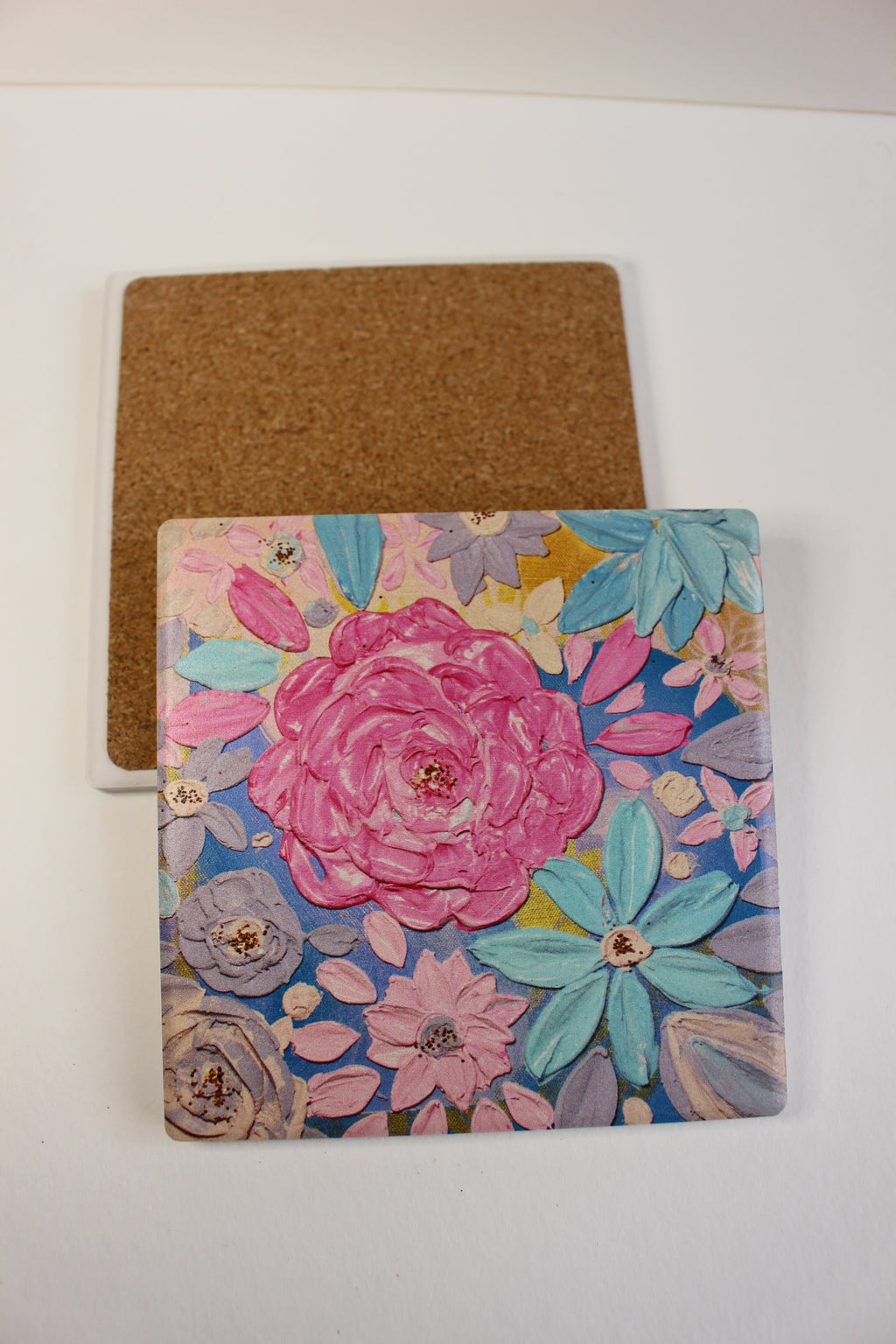 10x10cm square ceramic coaster featuring a colorful hand-painted floral art print with a protective cork backing.