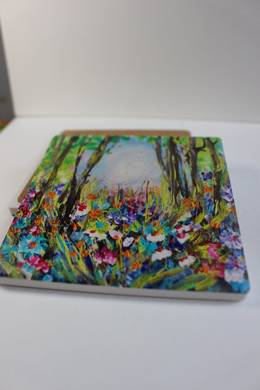 10x10cm square ceramic coaster featuring a colorful, hand-painted floral forest art print with a protective cork backing.